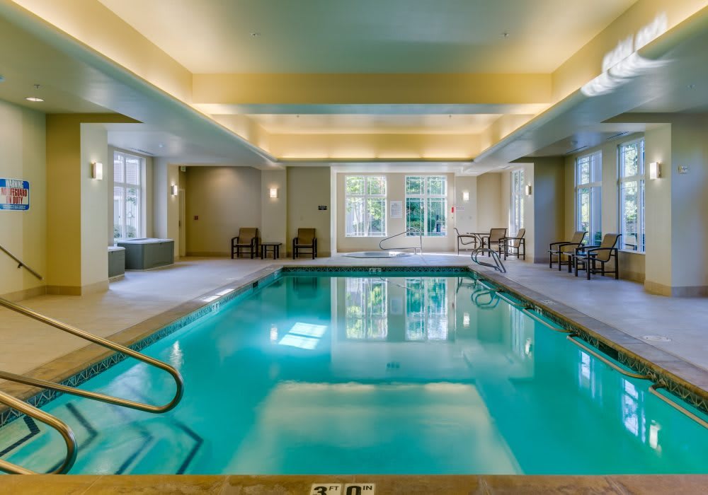 A serene indoor swimming pool area with seating and natural light.