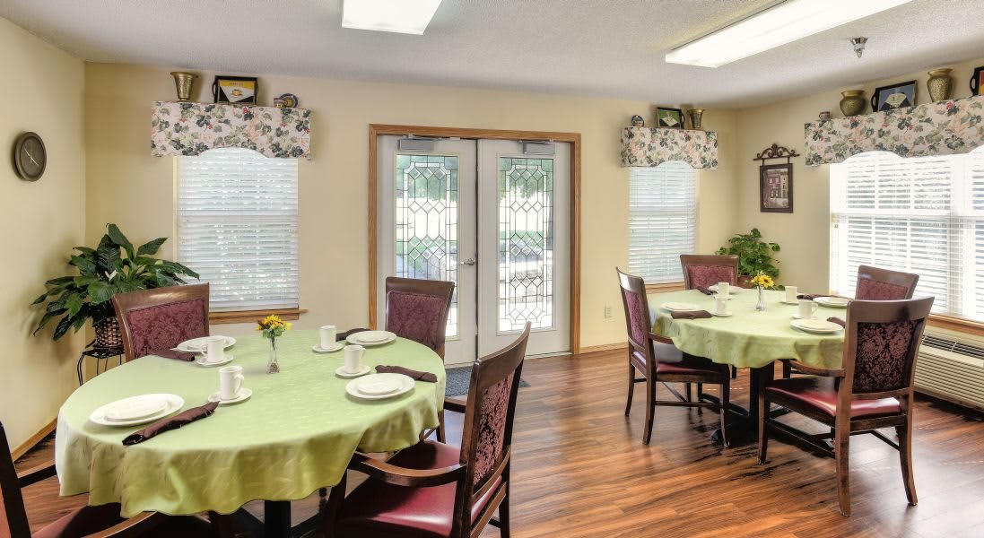 A cozy dining room with set tables and wooden flooring.
