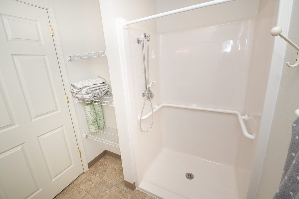 An accessible walk-in shower with grab bars and towels neatly arranged on a shelf.