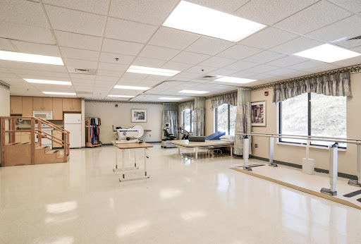 A spacious and well-lit medical room designed for rehabilitation, featuring various equipment and a calming environment.