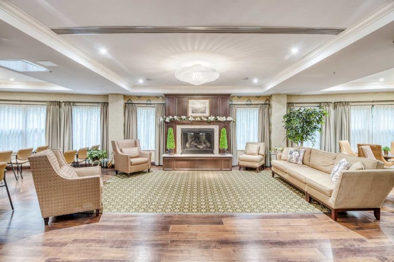 A spacious living room with a fireplace, elegant furniture, and a chandelier.