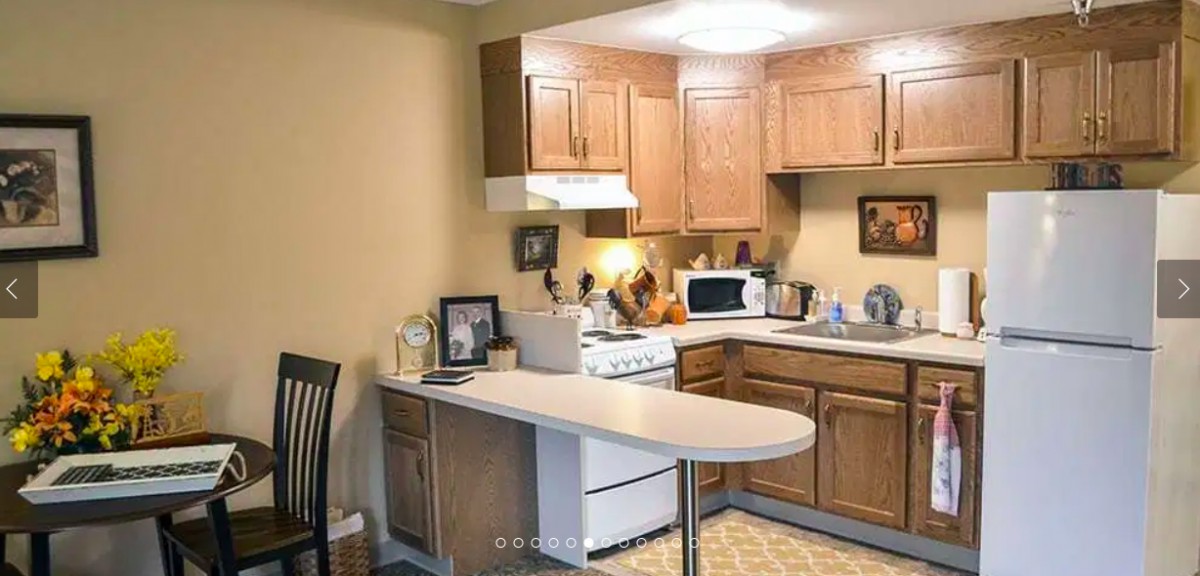 A cozy kitchen with wooden cabinets and a countertop, featuring a stove and microwave.