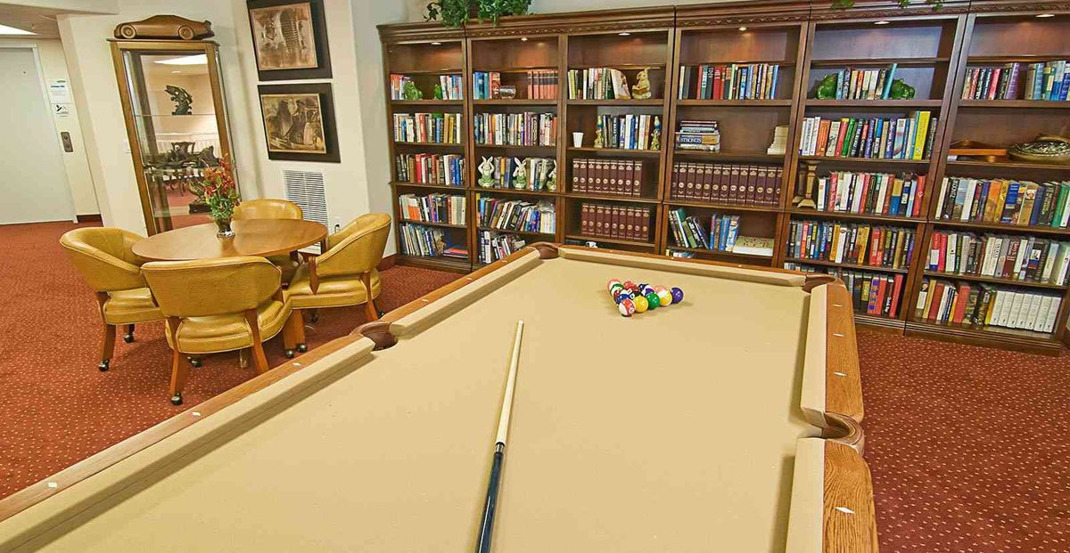 A cozy room with a pool table and bookshelves filled with books.