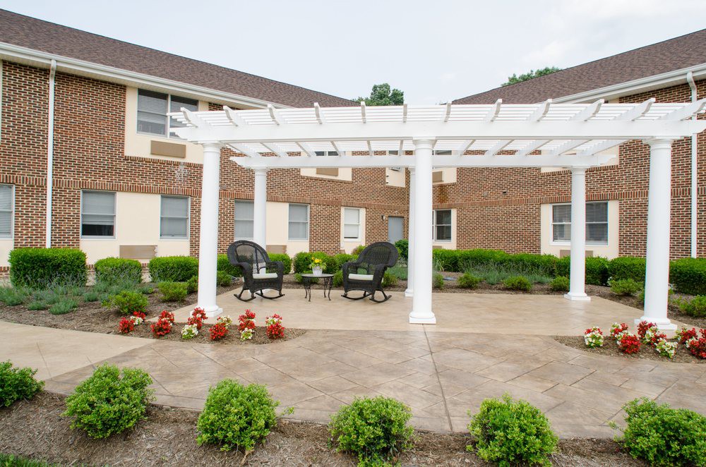 A patio area with a white pergola and outdoor seating in a garden setting.