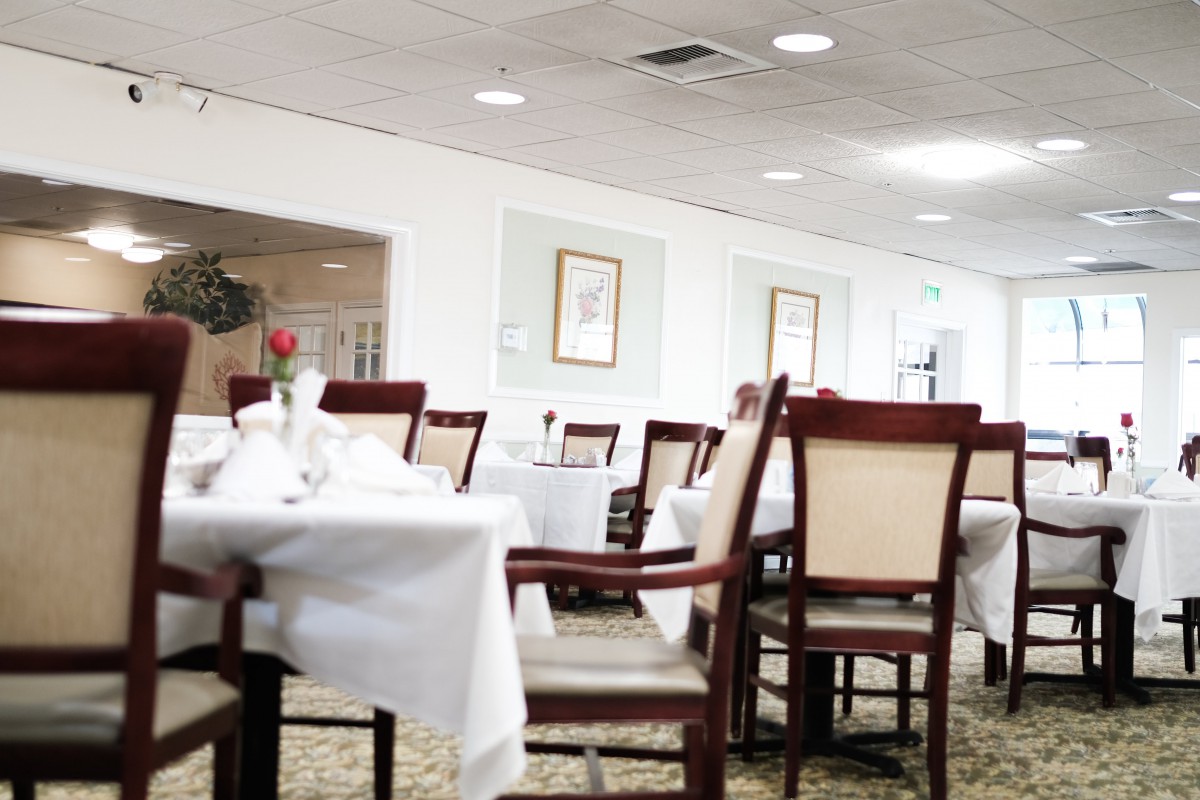 An empty restaurant dining room with neatly arranged tables and chairs.