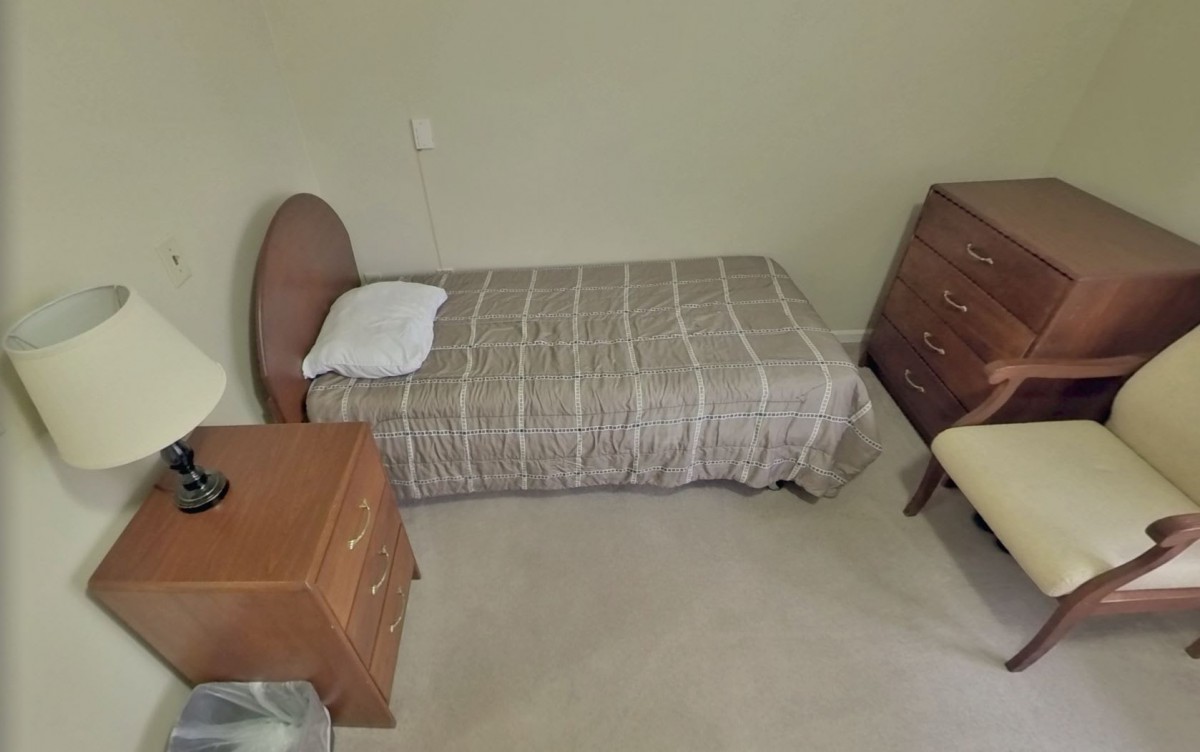 A simple bedroom with a single bed, dresser, and nightstand.