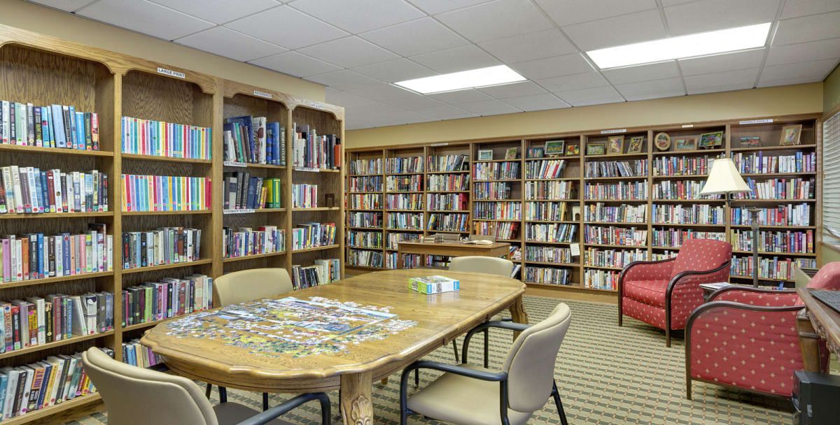 A quiet library room with shelves full of books and a table surrounded by chairs.