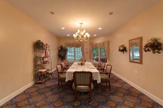 A cozy dining room with a central table, elegant chairs, and a chandelier.