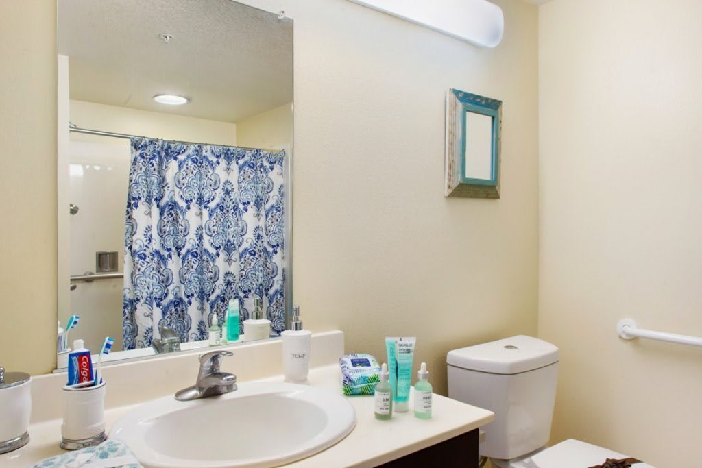A clean and organized bathroom featuring a sink, toilet, and blue patterned shower curtain.