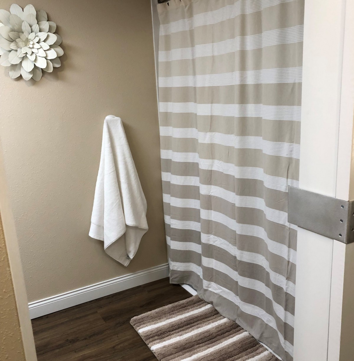 A cozy bathroom with a striped shower curtain and matching bath mat.