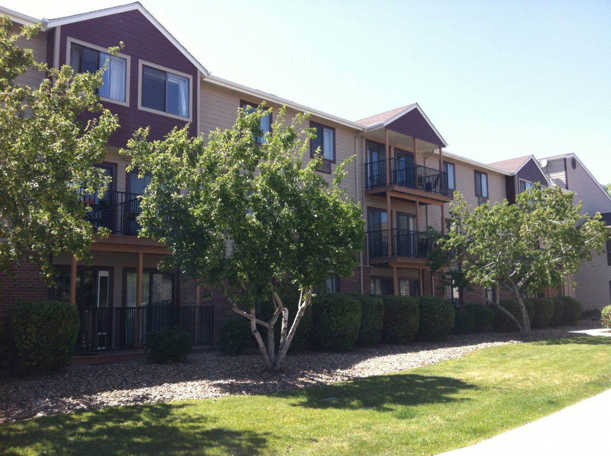 A sunny view of a residential apartment building surrounded by greenery.