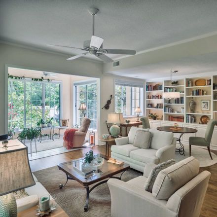 A cozy and modern living room filled with natural light, featuring comfortable furniture and well-organized bookshelves.