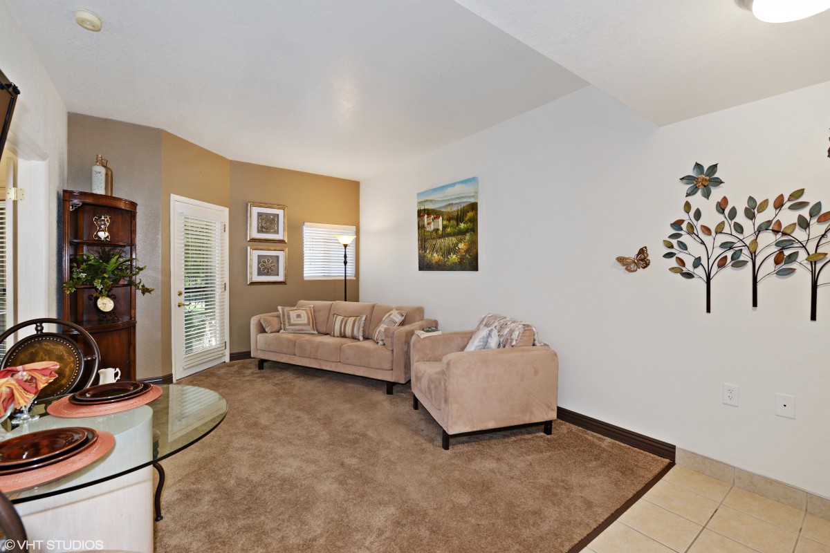 A modern living room with a beige sofa, artwork on the walls, and a cozy carpet.
