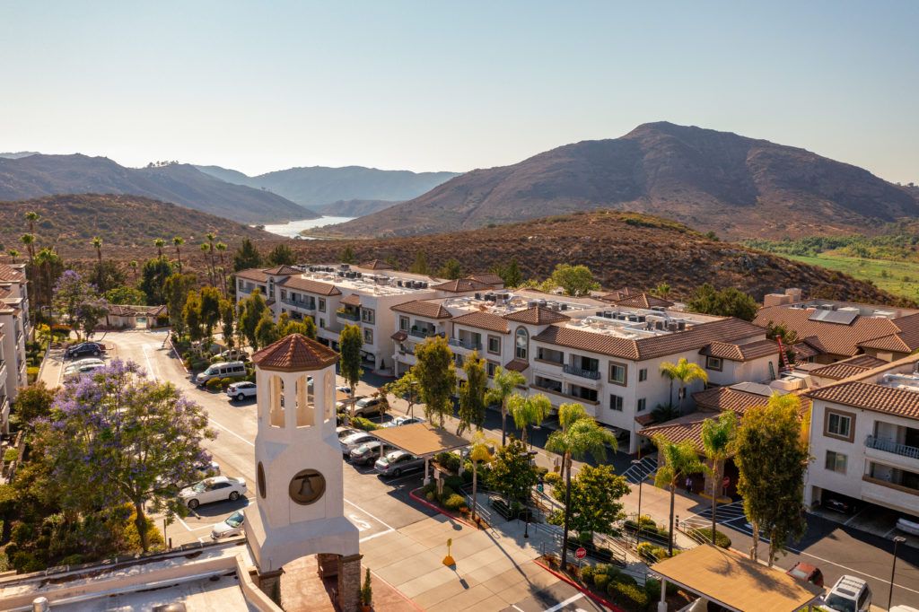 A scenic view of a clock tower with mountains in the background on a sunny day.