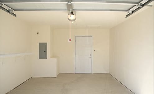 An empty garage with a door and a ceiling light fixture.