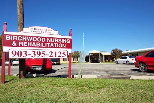 An exterior view of the Elmwood Nursing Rehabilitation facility with a prominent sign.