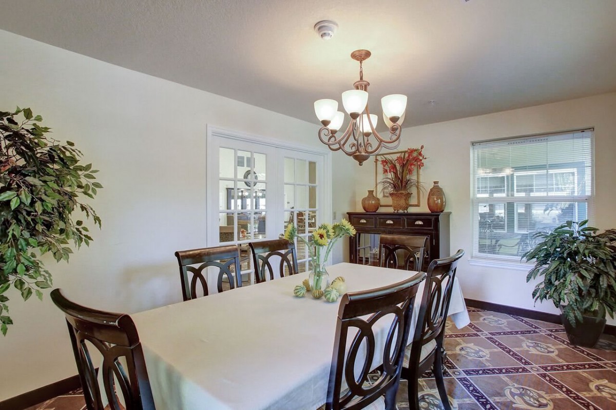 A well-decorated dining room with a table set for a meal, featuring an elegant chandelier and tasteful decor.
