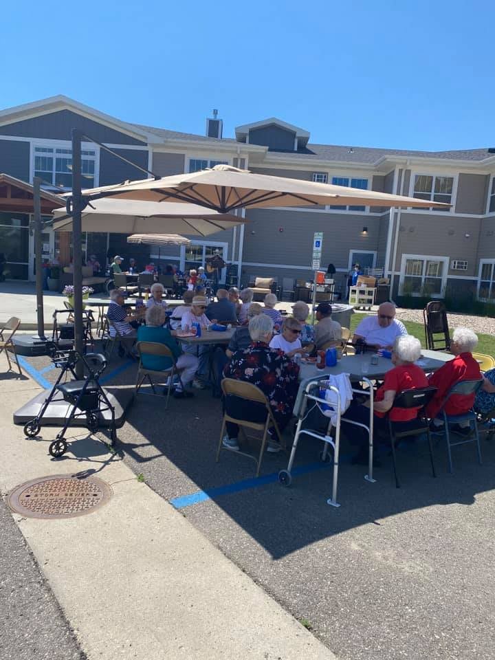 A group of people enjoying an outdoor gathering under umbrellas on a sunny day.