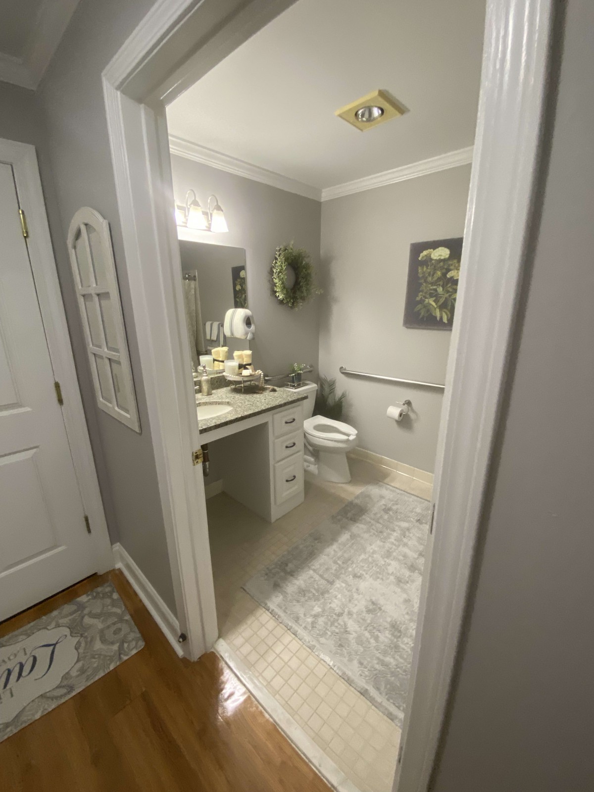 A well-decorated bathroom featuring a vanity with a mirror, gray walls, and a cozy ambiance.