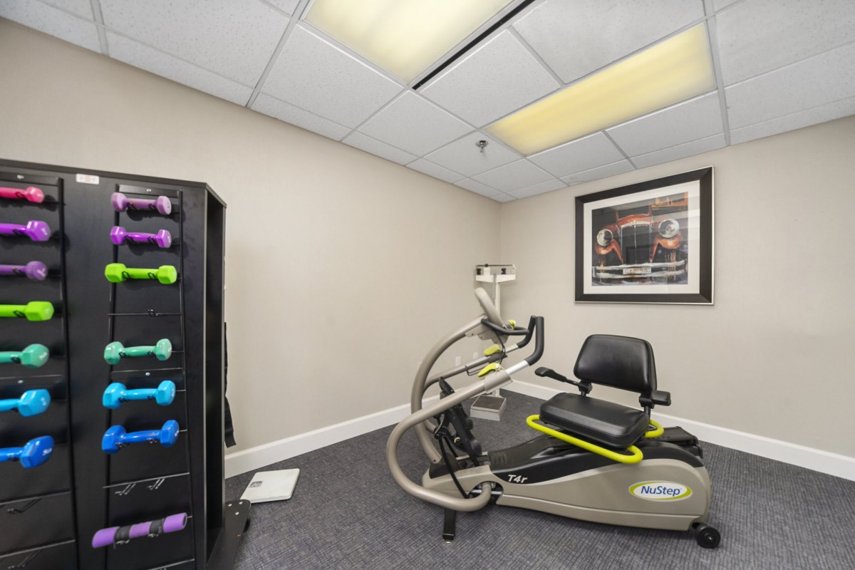 A small exercise room featuring a stationary bike and a rack of dumbbells.