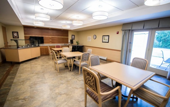 An empty dining area with tables and chairs arranged neatly in a well-lit space.