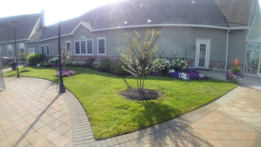 A well-maintained garden featuring a manicured lawn and blooming flowers beside a house.