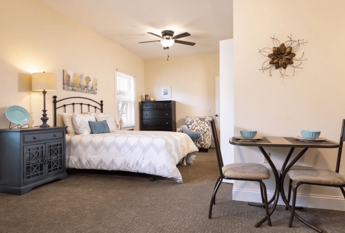 A cozy bedroom with a bed, small dining table, and tasteful decor.