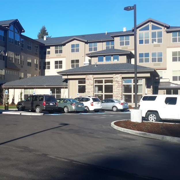 A view of a multi-story residential building with cars parked outside on a sunny day.