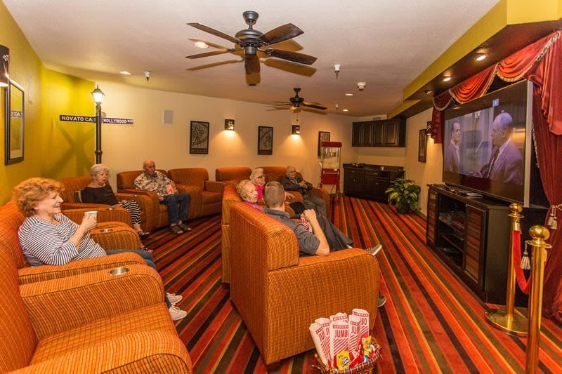 A cozy home theater room with comfortable seating and a large television, where people are enjoying a movie together.