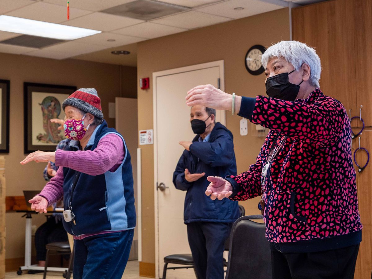 A group of seniors participating in an indoor exercise class while wearing masks.