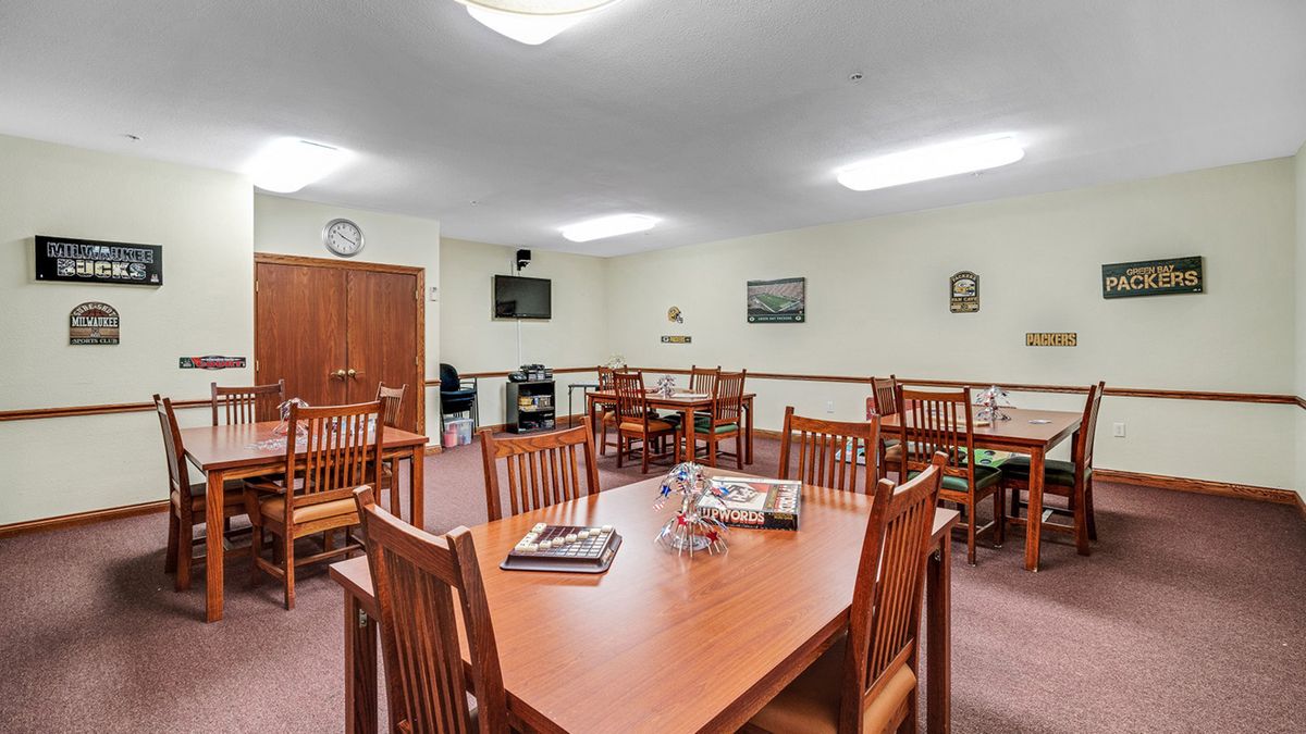 An indoor meeting room with multiple tables and chairs arranged for seating.