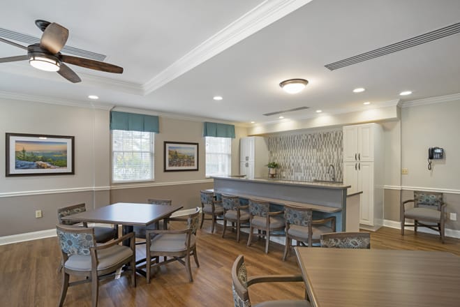 A modern dining area featuring multiple tables and chairs, with elegant lighting and wood flooring.