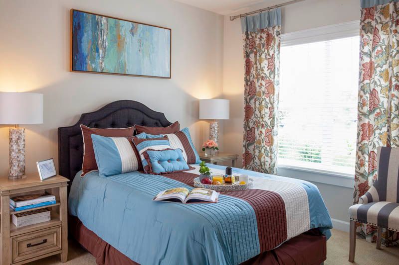 A cozy bedroom with a neatly made bed, colorful pillows, and a decorative painting on the wall.