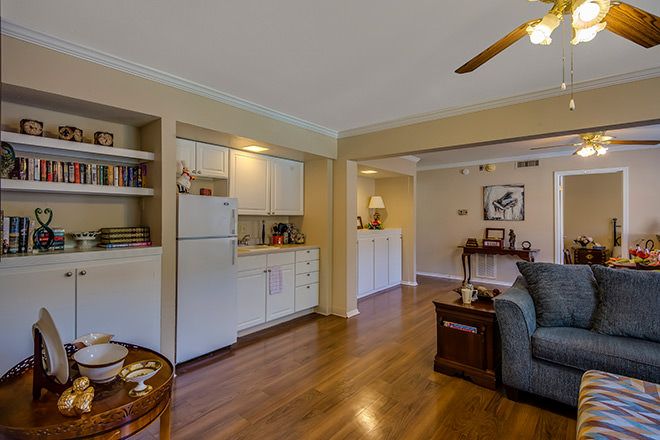 A cozy living room with a kitchenette, hardwood floors, and comfortable furnishings.