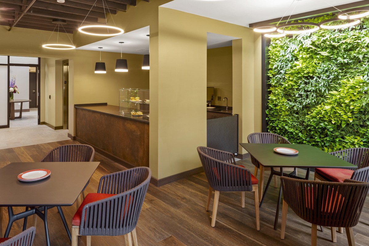 A modern cafe interior featuring stylish furniture and a green vertical wall.