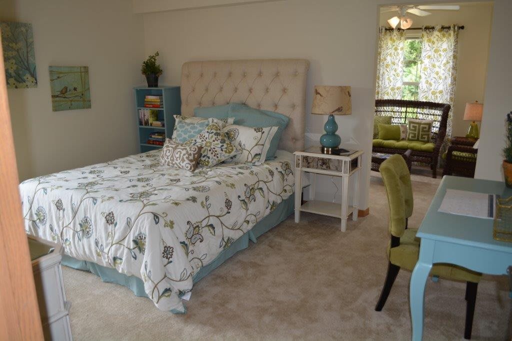 A cozy bedroom with a neatly made bed, decorative pillows, and stylish furniture.