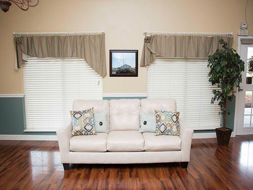 A cozy living room featuring a light-colored sofa with decorative pillows, wooden flooring, and elegant curtains.
