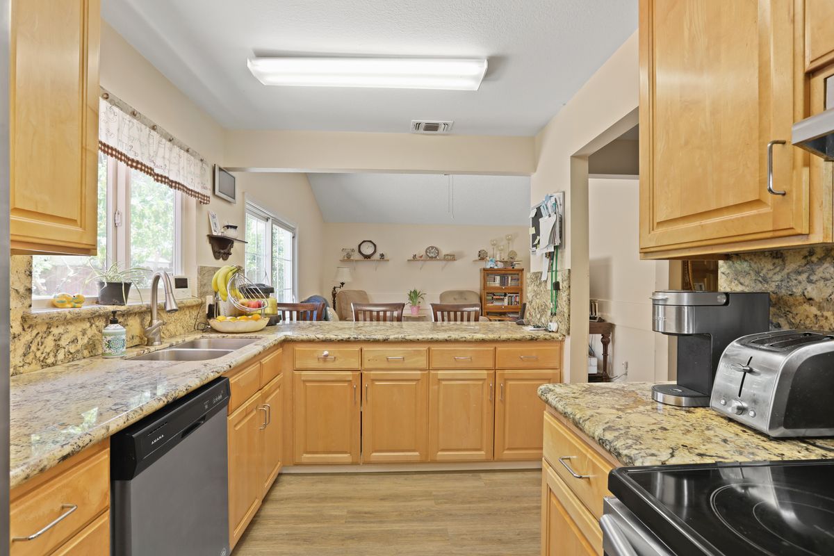 A spacious kitchen with wooden cabinets, granite countertops, and modern appliances in an open-concept design.