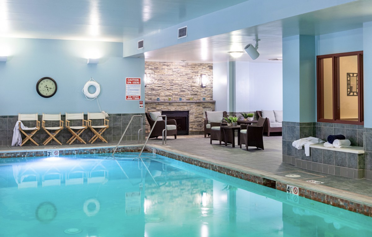 A modern indoor pool area with comfortable seating and a cozy fireplace.