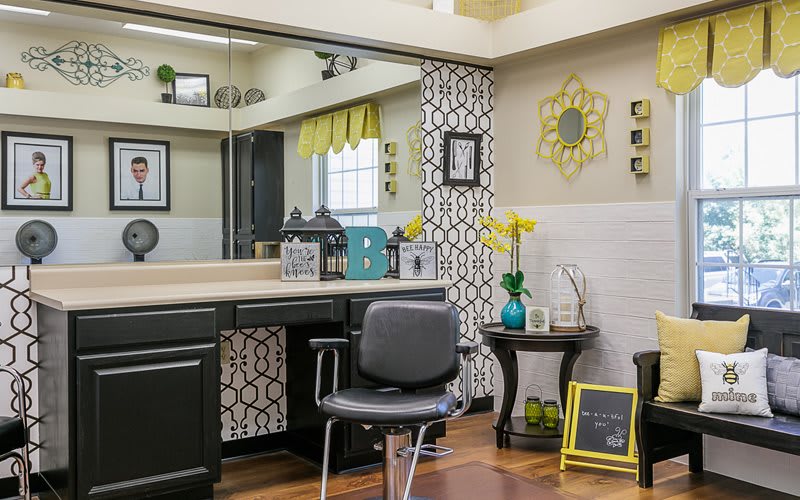 A modern hair salon with stylish decor, featuring a mirror, chair, and floral accents.