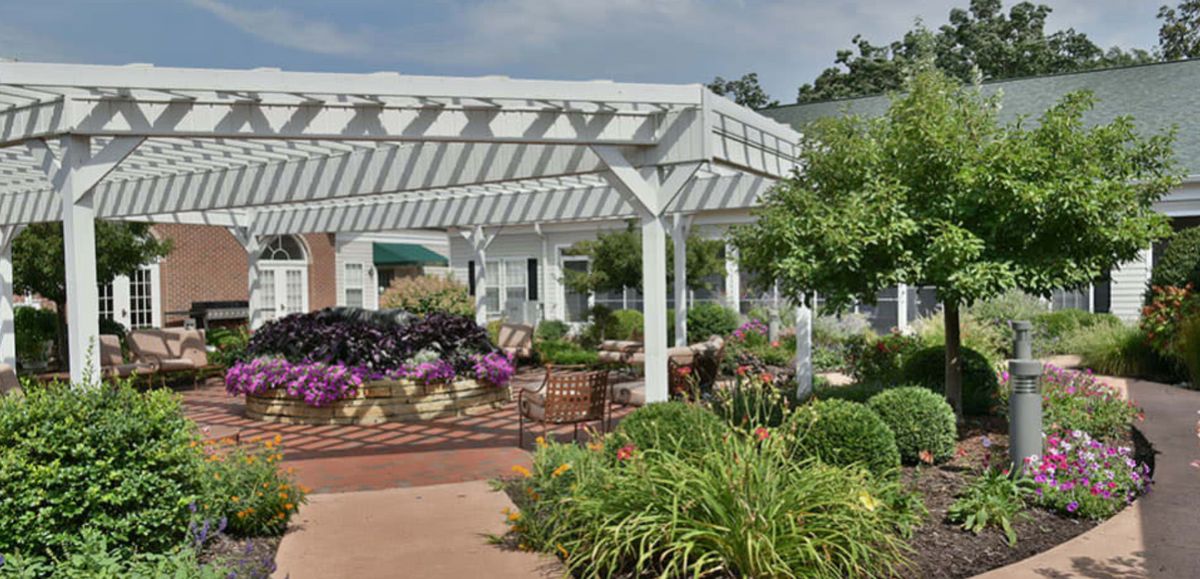 A beautifully landscaped garden featuring a white pergola and vibrant flowers.