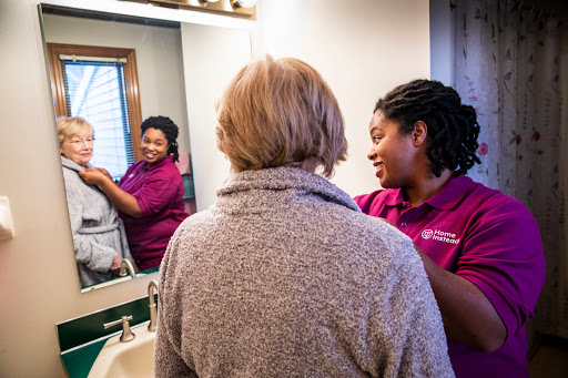 A woman receives personal care in a cozy bathroom setting, highlighting a moment of connection and support.