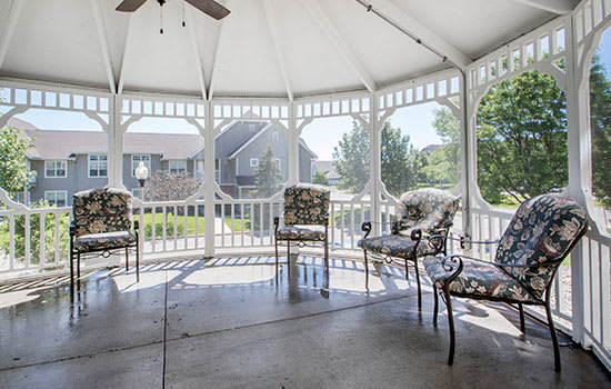 A spacious gazebo with elegant patio furniture, offering a serene garden view.