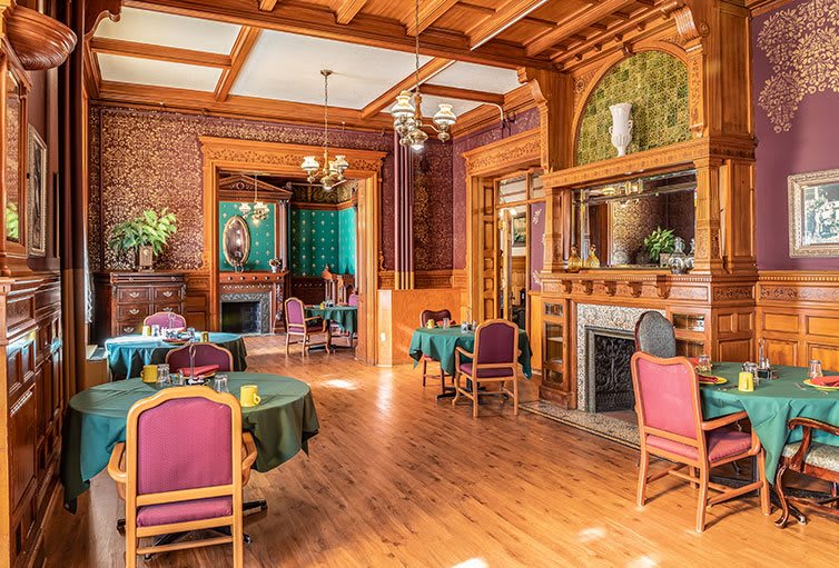 A vintage-style restaurant interior featuring wooden decor, elegant tables, and a cozy fireplace.