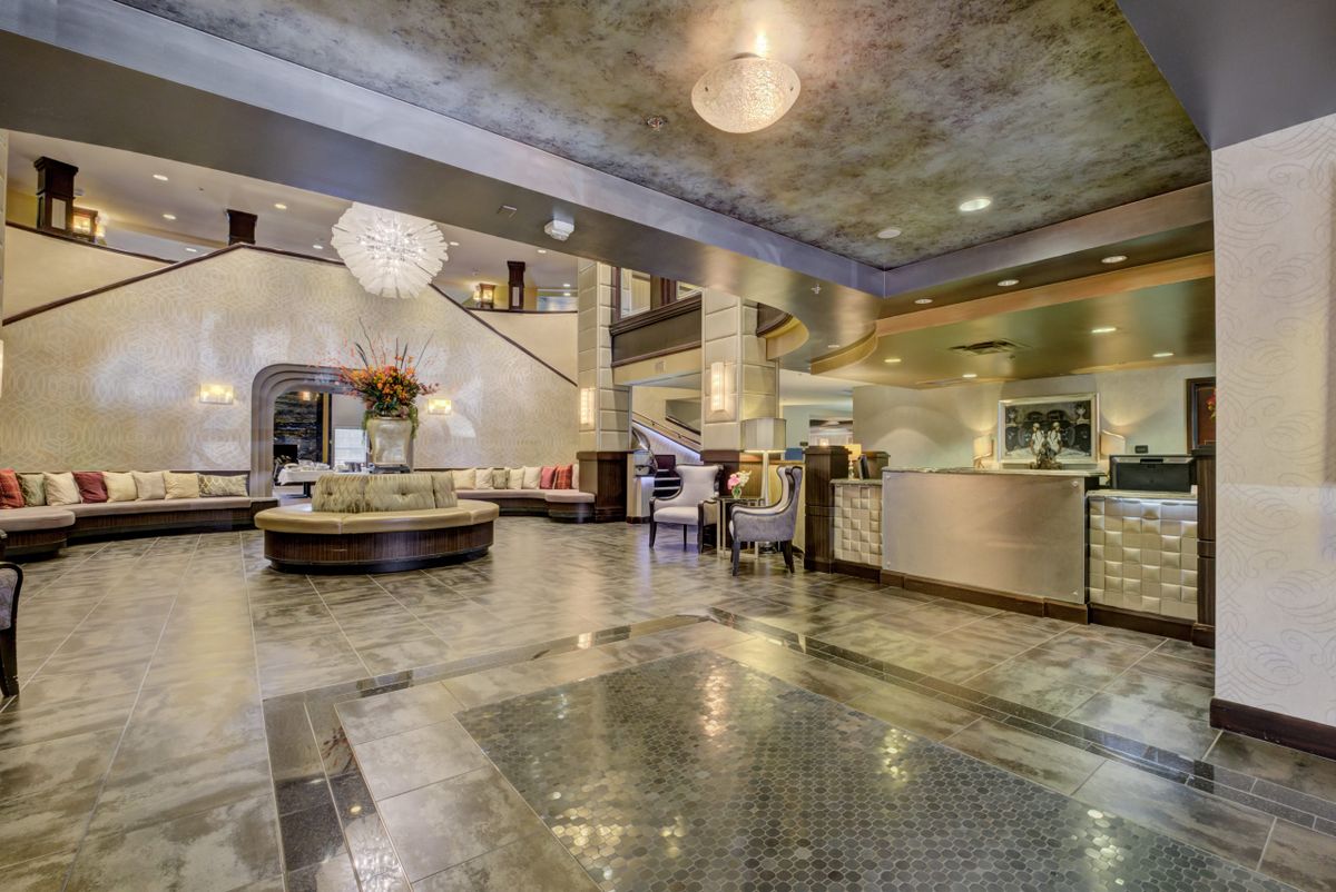A luxurious hotel lobby featuring a grand chandelier, elegant reception desk, and stylish furnishings.