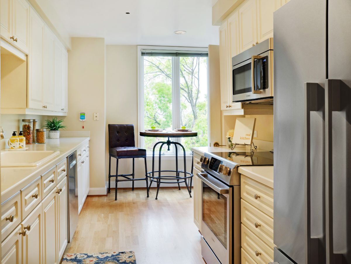 A modern kitchen with stainless steel appliances and a small dining area by the window.