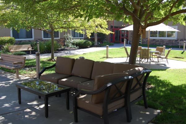 A cozy outdoor patio area with comfortable seating and shaded by trees.