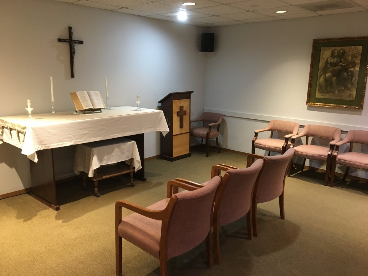 A small chapel interior with an altar, cross, and seating.