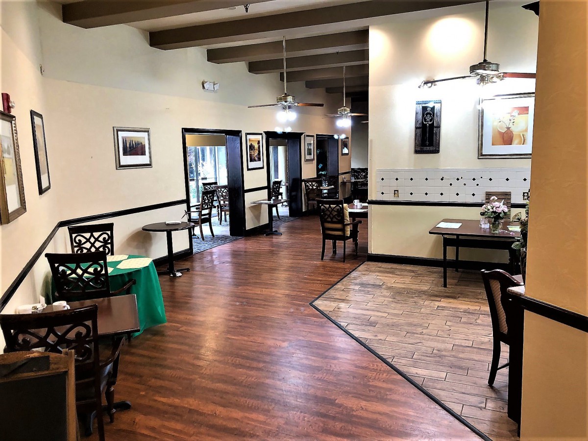 An empty restaurant interior with wooden flooring and neatly arranged tables.