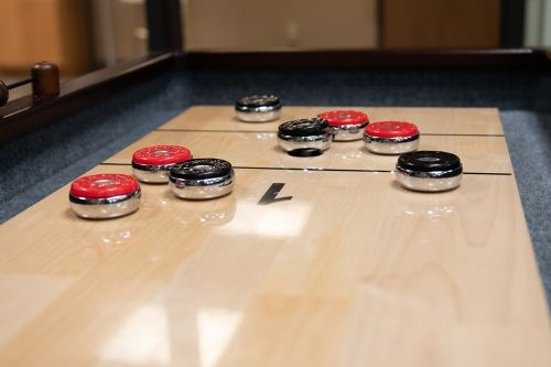 A close-up view of a shuffleboard table with pucks in play.